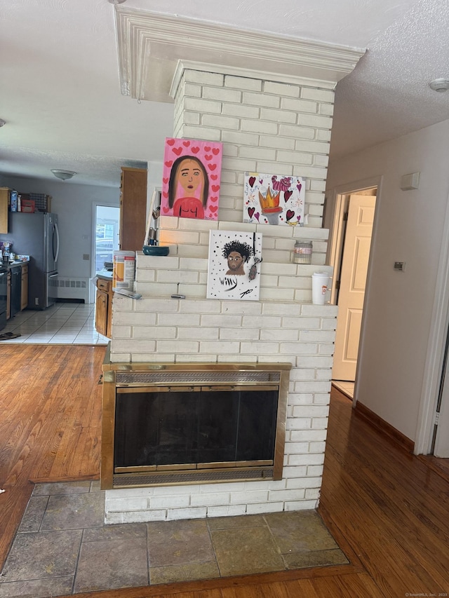 129 Monroe St, East Hartford, CT 06118 - detailed view of wood finished floors, baseboards, freestanding refrigerator, a textured ceiling, and a fireplace