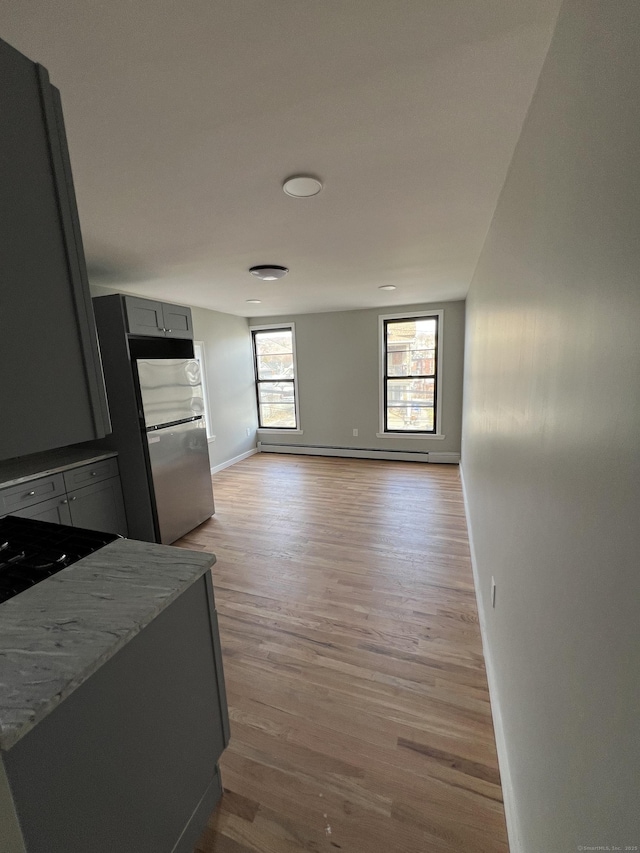 49 Hill St, Waterbury, CT 06704 - kitchen with light wood-style floors, baseboards, freestanding refrigerator, cooktop, and a baseboard radiator