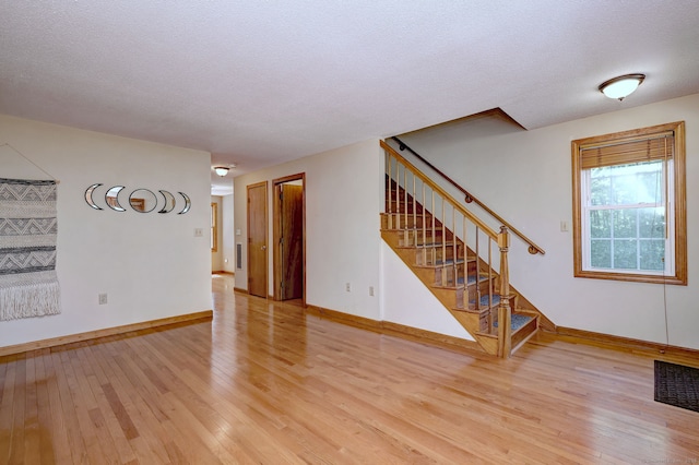 37 White Tail Ln Unit 37, Wallingford, CT 06492 - unfurnished living room featuring light wood-type flooring, baseboards, stairway, and a textured ceiling