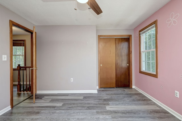 37 White Tail Ln Unit 37, Wallingford, CT 06492 - unfurnished bedroom with multiple windows, wood finished floors, baseboards, a closet, and a textured ceiling