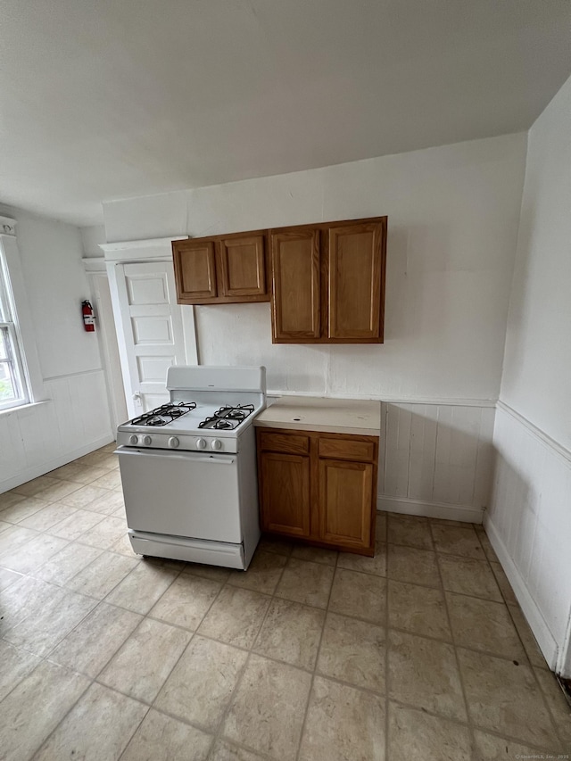 865 Elm St, New Haven, CT 06511 - kitchen with white gas range, brown cabinets, wainscoting, and light countertops