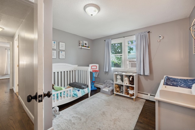 29 Carson Ave, Wethersfield, CT 06109 - bedroom with dark wood-style floors, baseboard heating, a textured ceiling, and a crib