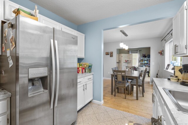 167 Santa Maria Dr, Torrington, CT 06790 - kitchen with stainless steel refrigerator with ice dispenser, white cabinets, light countertops, granite tiled floors, and baseboards
