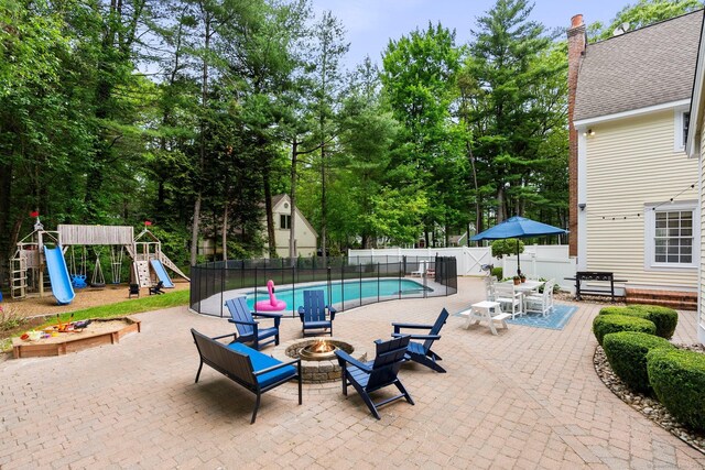 27 Chiltern St, Farmington, CT 06032 - view of swimming pool with an outdoor fire pit, a fenced backyard, a patio area, a playground, and view of wooded area
