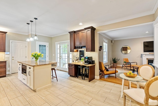 27 Chiltern St, Farmington, CT 06032 - kitchen featuring a kitchen bar, stainless steel microwave, light stone countertops, decorative light fixtures, and ornamental molding