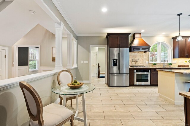 27 Chiltern St, Farmington, CT 06032 - kitchen featuring stainless steel appliances, ornate columns, custom range hood, tasteful backsplash, and dark brown cabinets