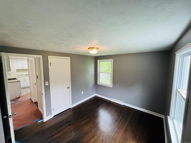 10 Bozrah St, Bozrah, CT 06334 - unfurnished bedroom with baseboards, dark wood-style floors, a baseboard radiator, and a textured ceiling