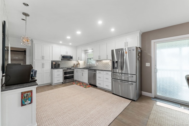 6 Meadow Dr, Waterford, CT 06385 - kitchen featuring stainless steel appliances, a sink, decorative backsplash, dark countertops, and light wood finished floors