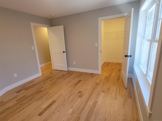 82 Ladd Rd, Tolland, CT 06084 - unfurnished bedroom with a walk in closet, light wood-type flooring, a closet, and multiple windows