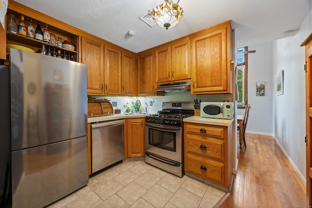 58 Woodley Ct Unit 14, Meriden, CT 06450 - kitchen with appliances with stainless steel finishes, under cabinet range hood, light countertops, brown cabinetry, and a sink