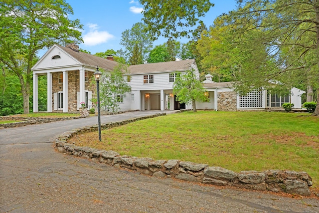 16 Katydid Ln, Weston, CT 06883 - greek revival house featuring stone siding, driveway, a chimney, and a front lawn