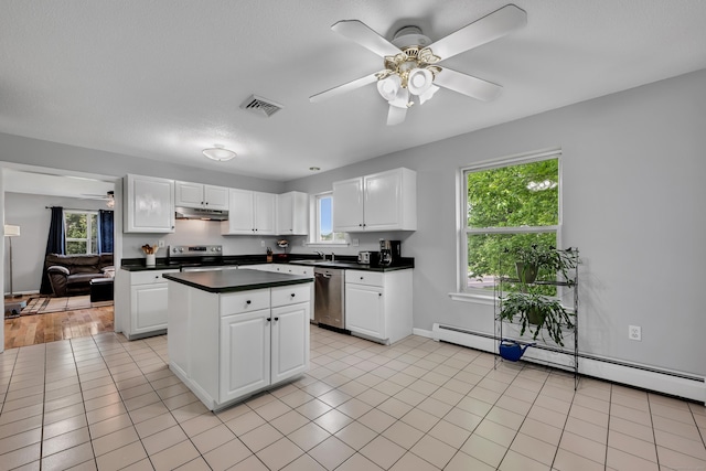 122 Carr Ave, Newington, CT 06111 - kitchen with a ceiling fan, appliances with stainless steel finishes, under cabinet range hood, a kitchen island, and dark countertops