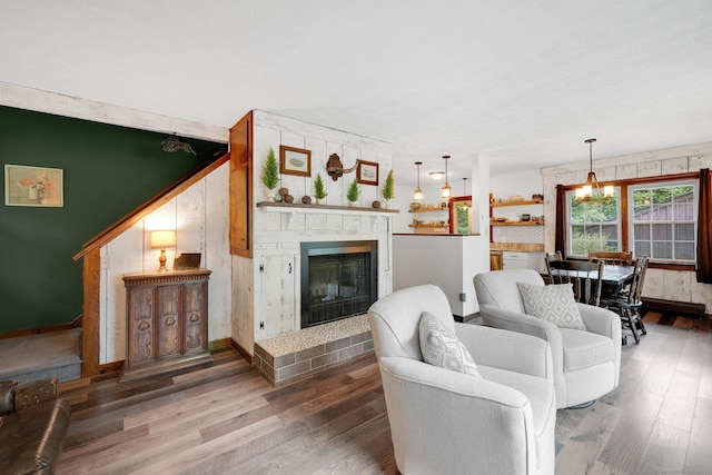 55 Indian Spring Rd, Woodstock, CT 06281 - living area featuring a glass covered fireplace, wood finished floors, baseboards, wooden walls, and a chandelier