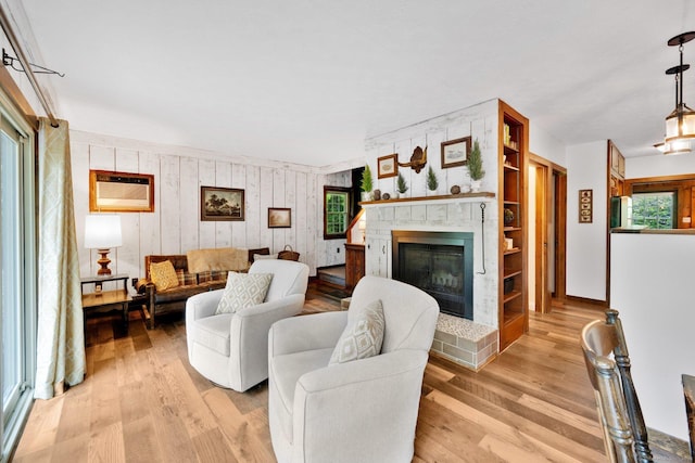 55 Indian Spring Rd, Woodstock, CT 06281 - living area featuring a glass covered fireplace, light wood-type flooring, wooden walls, and a wall unit AC