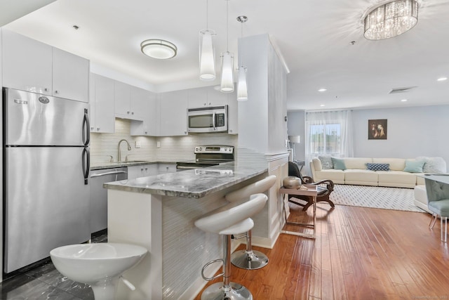1633 Washington Blvd Unit 3A, Stamford, CT 06902 - kitchen with stainless steel appliances, a peninsula, a sink, stone countertops, and pendant lighting