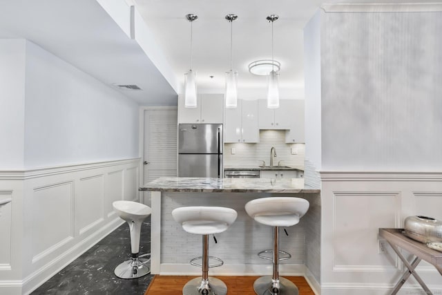 1633 Washington Blvd Unit 3A, Stamford, CT 06902 - kitchen featuring stainless steel appliances, a sink, a breakfast bar, a decorative wall, and white cabinetry