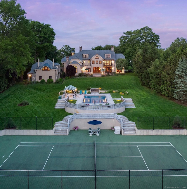 61 High Ridge Ave, Ridgefield, CT 06877 - back of property at dusk with a tennis court, a chimney, and stairs