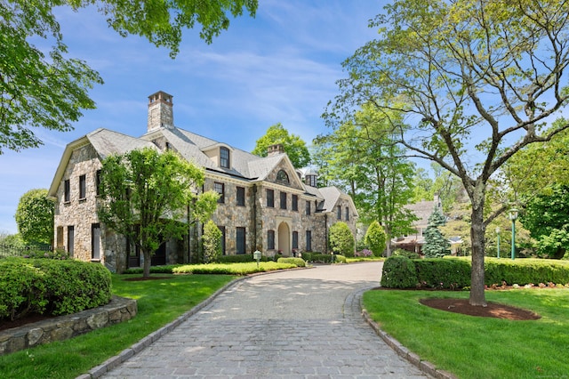 61 High Ridge Ave, Ridgefield, CT 06877 - view of front of house featuring stone siding, a chimney, a front lawn, curved driveway, and a high end roof