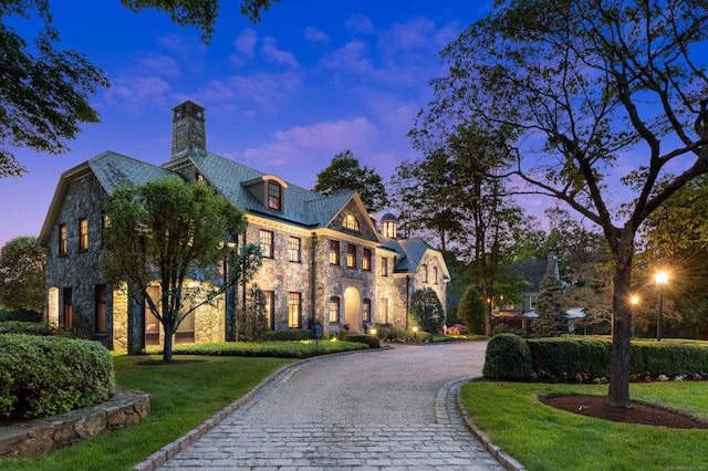 61 High Ridge Ave, Ridgefield, CT 06877 - view of front of house with stone siding, a chimney, a high end roof, curved driveway, and a front lawn