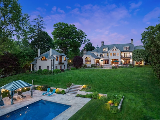 61 High Ridge Ave, Ridgefield, CT 06877 - back of house at dusk featuring a gazebo, a yard, a patio area, a chimney, and an outdoor pool