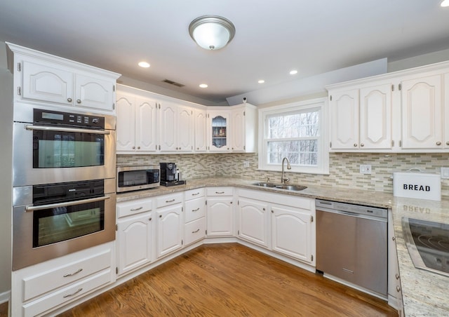 498 Nod Hill Rd, Wilton, CT 06897 - kitchen with a sink, appliances with stainless steel finishes, light wood finished floors, white cabinets, and decorative backsplash