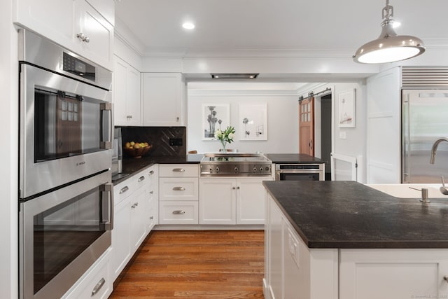 63 Fitch Ln, New Canaan, CT 06840 - kitchen with appliances with stainless steel finishes, a barn door, white cabinets, wood finished floors, and recessed lighting