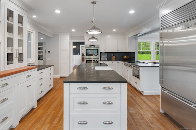 63 Fitch Ln, New Canaan, CT 06840 - kitchen with appliances with stainless steel finishes, ornamental molding, glass insert cabinets, dark countertops, and recessed lighting