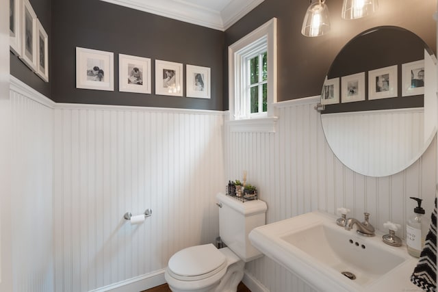 63 Fitch Ln, New Canaan, CT 06840 - half bathroom featuring toilet, a wainscoted wall, a sink, crown molding, and a decorative wall