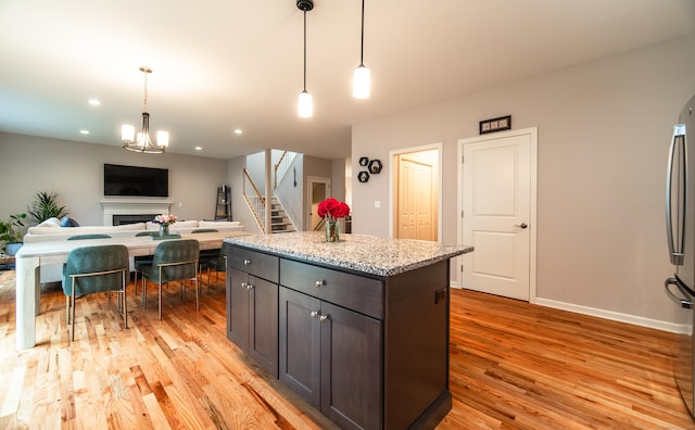 2 Redwood Ln, Southington, CT 06489 - kitchen featuring light wood finished floors, a fireplace, hanging light fixtures, open floor plan, and light stone countertops