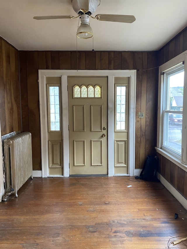 624 S Main St, Torrington, CT 06790 - foyer featuring radiator, wooden walls, a ceiling fan, wood finished floors, and baseboards
