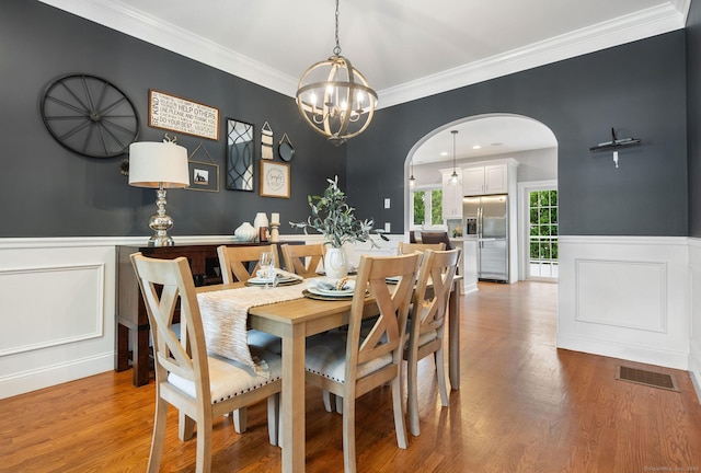48 Evergreen Rd, Cromwell, CT 06416 - dining space with arched walkways, a chandelier, a decorative wall, light wood-style flooring, and wainscoting