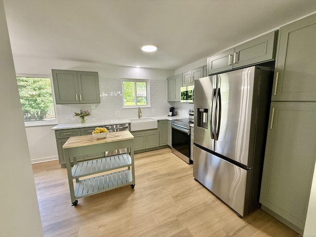 740 Heritage Vlg Unit B, Southbury, CT 06488 - kitchen with appliances with stainless steel finishes, green cabinetry, a sink, and decorative backsplash