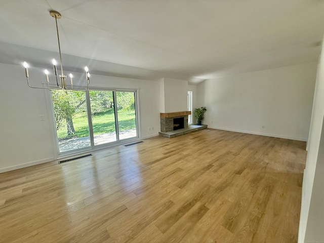 740 Heritage Vlg Unit B, Southbury, CT 06488 - unfurnished living room featuring light wood-type flooring, a chandelier, baseboards, and a stone fireplace