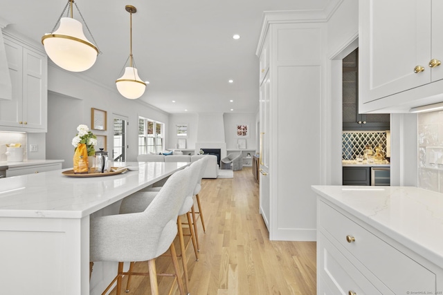 15 Barton Rd, Fairfield, CT 06824 - kitchen with tasteful backsplash, light wood-type flooring, white cabinetry, a breakfast bar, and a fireplace