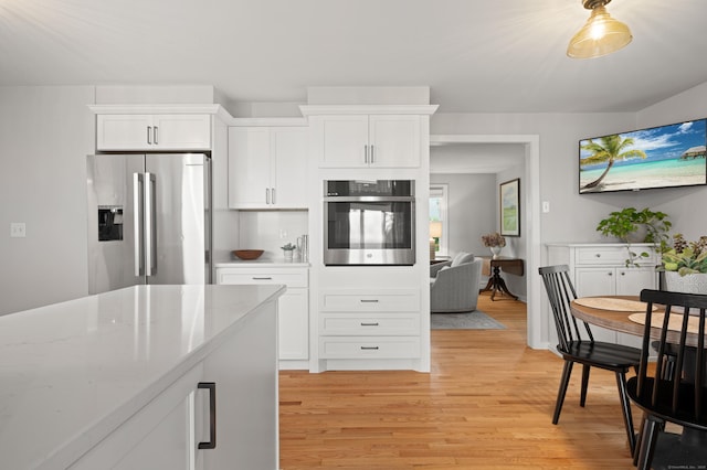 55 Cypress Rd, Old Saybrook, CT 06475 - kitchen featuring appliances with stainless steel finishes, light wood finished floors, white cabinets, and light stone countertops