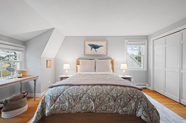 55 Cypress Rd, Old Saybrook, CT 06475 - bedroom with multiple windows, a closet, a baseboard radiator, and light wood-style flooring