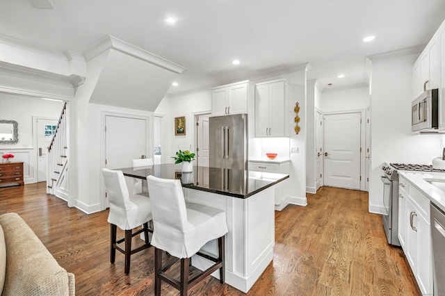 2180 Kings Hwy Unit 1, Fairfield, CT 06824 - kitchen with appliances with stainless steel finishes, a breakfast bar, white cabinets, a center island, and wood finished floors