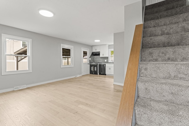 32 Porterbrook Ave, East Hartford, CT 06118 - unfurnished living room featuring stairs, light wood-style flooring, plenty of natural light, and baseboards