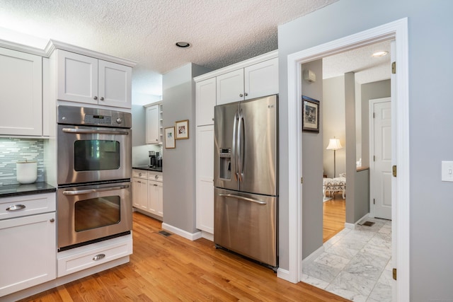 53 Bathcrescent Ln Unit 53, Bloomfield, CT 06002 - kitchen featuring appliances with stainless steel finishes, dark countertops, decorative backsplash, baseboards, and a textured ceiling