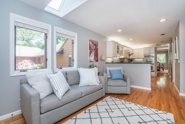 53 Bathcrescent Ln Unit 53, Bloomfield, CT 06002 - living room featuring a skylight, plenty of natural light, light wood-type flooring, baseboards, and recessed lighting