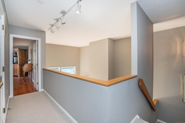 53 Bathcrescent Ln Unit 53, Bloomfield, CT 06002 - hallway with an upstairs landing, baseboards, a textured ceiling, rail lighting, and carpet floors