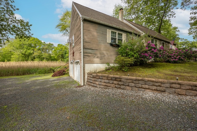76 River St W, Old Saybrook, CT 06475 - view of side of property with a chimney, a garage, and driveway