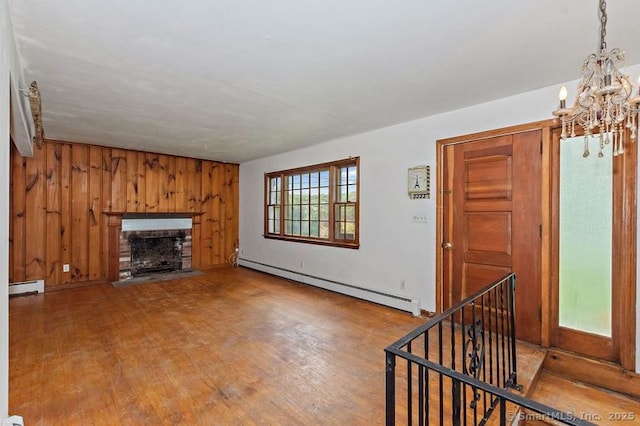 3 Pattagansett Ct, East Lyme, CT 06357 - unfurnished living room with a baseboard radiator, a chandelier, wood finished floors, a brick fireplace, and wood walls