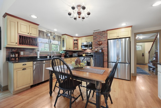 50 Clinton St, Glastonbury, CT 06033 - kitchen featuring appliances with stainless steel finishes, cream cabinetry, dark countertops, backsplash, and light wood-style floors