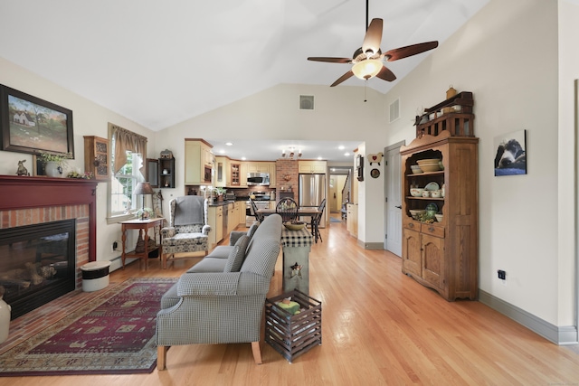 50 Clinton St, Glastonbury, CT 06033 - living room with vaulted ceiling, a ceiling fan, light wood finished floors, a brick fireplace, and baseboards