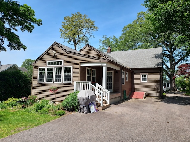 50 Clinton St, Glastonbury, CT 06033 - view of front facade with a chimney, a patio area, and a shingled roof