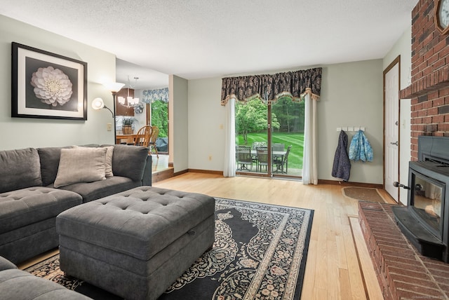 132 Royal Oak Dr, Southington, CT 06489 - living room featuring light wood finished floors, a chandelier, baseboards, a wood stove, and a textured ceiling