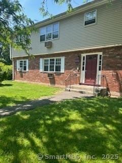 back of property with a yard and brick siding