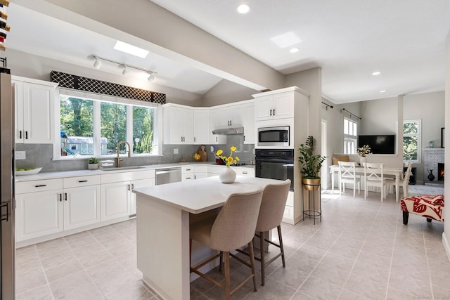 67 Old Farms Rd, Glastonbury, CT 06073 - kitchen with black appliances, under cabinet range hood, tasteful backsplash, light countertops, and a breakfast bar area