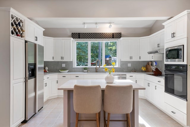 67 Old Farms Rd, Glastonbury, CT 06073 - kitchen with black appliances, a breakfast bar area, decorative backsplash, and light countertops